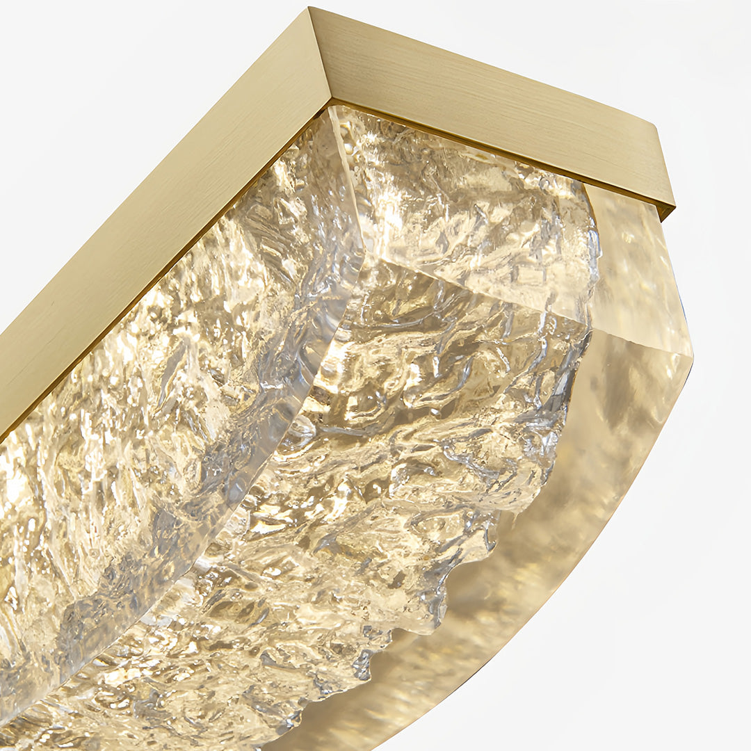 Close-up detail of large gold pendant light revealing layered crystal glass texture and golden frame.