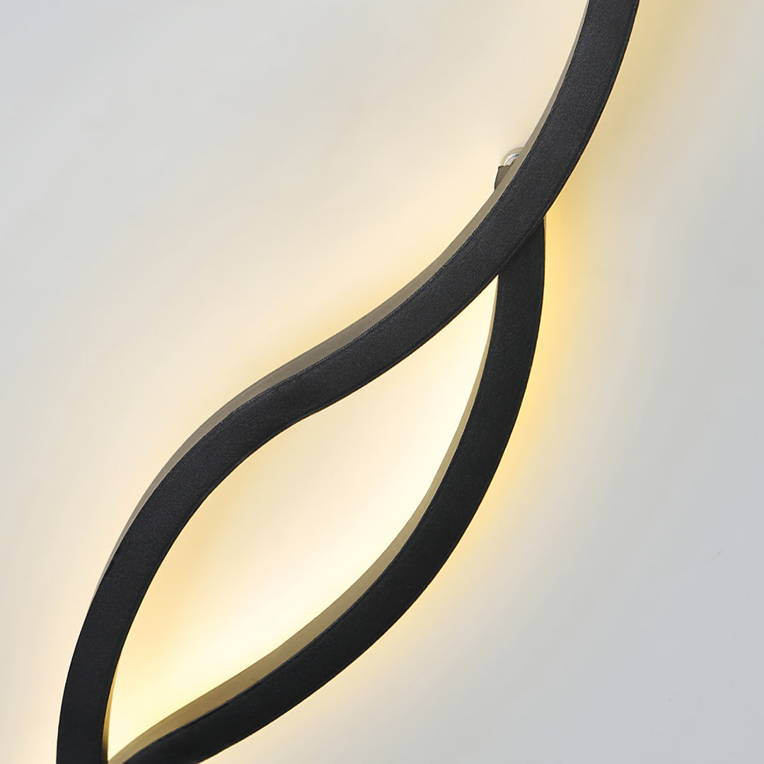 Close-up detail of the matte black finish and warm glow of the bedside wall light's curved design.