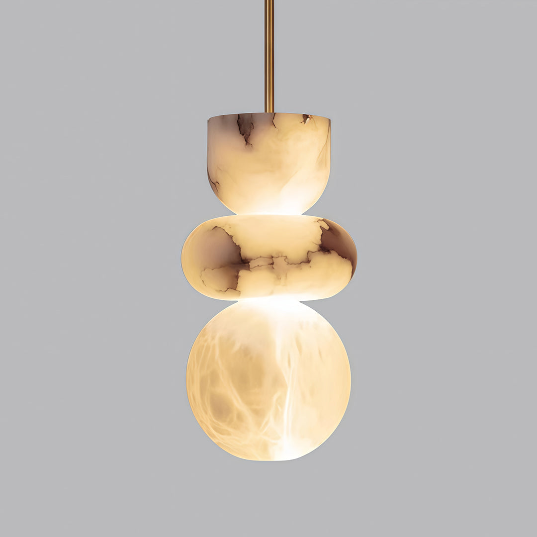 Close-up of minimalist pendant light with glass shade chandelier aesthetic showing glowing alabaster discs on dark background.