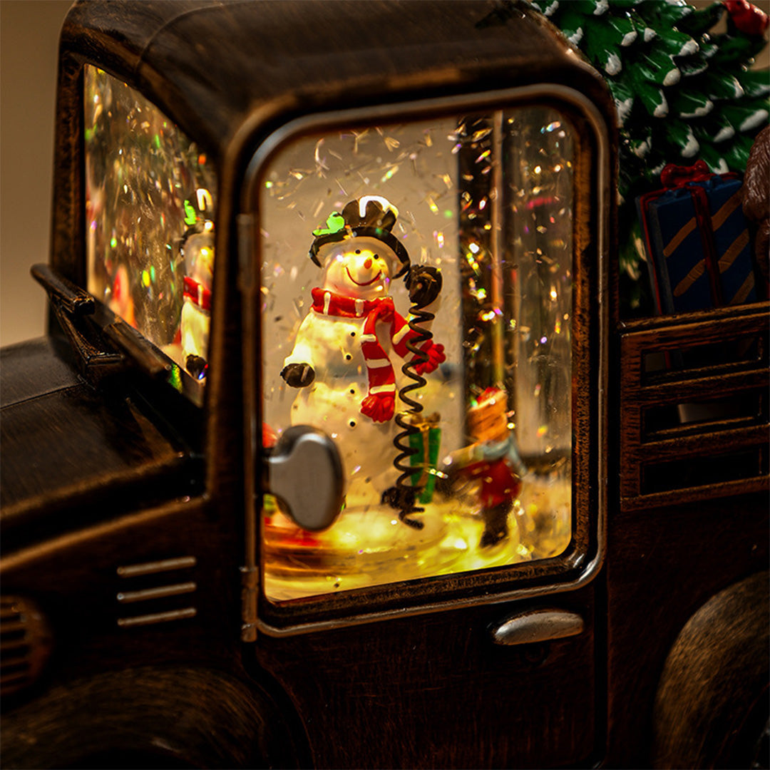 Close-up of illuminated truck window showing detailed Christmas scene with a soft modern gold table lamp glow.