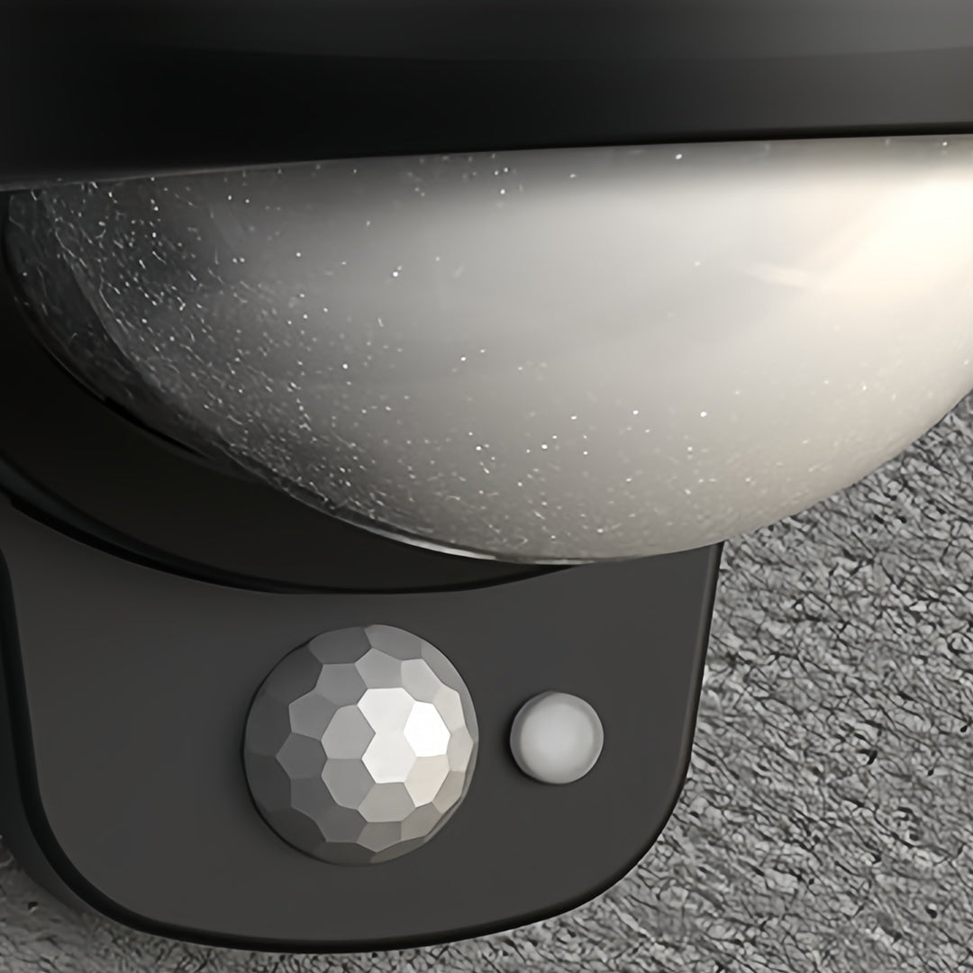 Close-up of vintage outdoor wall lights with sensor and curved lens detail.