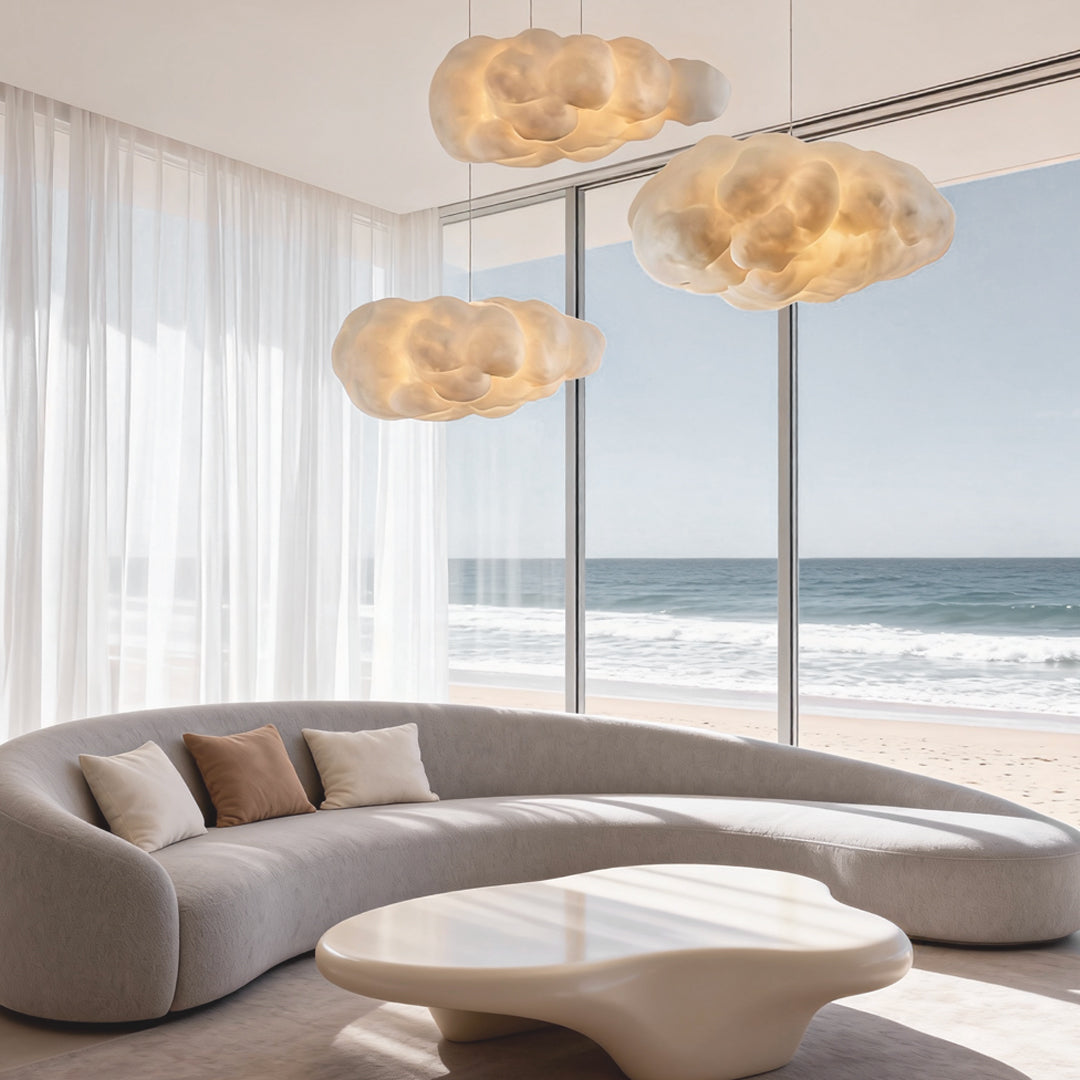 Elegant cloud pendant lights hanging near large windows in a seaside living room.