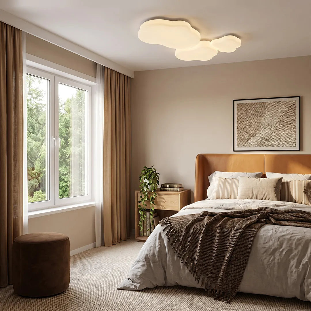 Cloud shaped ceiling light installed in a cozy bedroom with layered bedding, wood accents, and large windows.