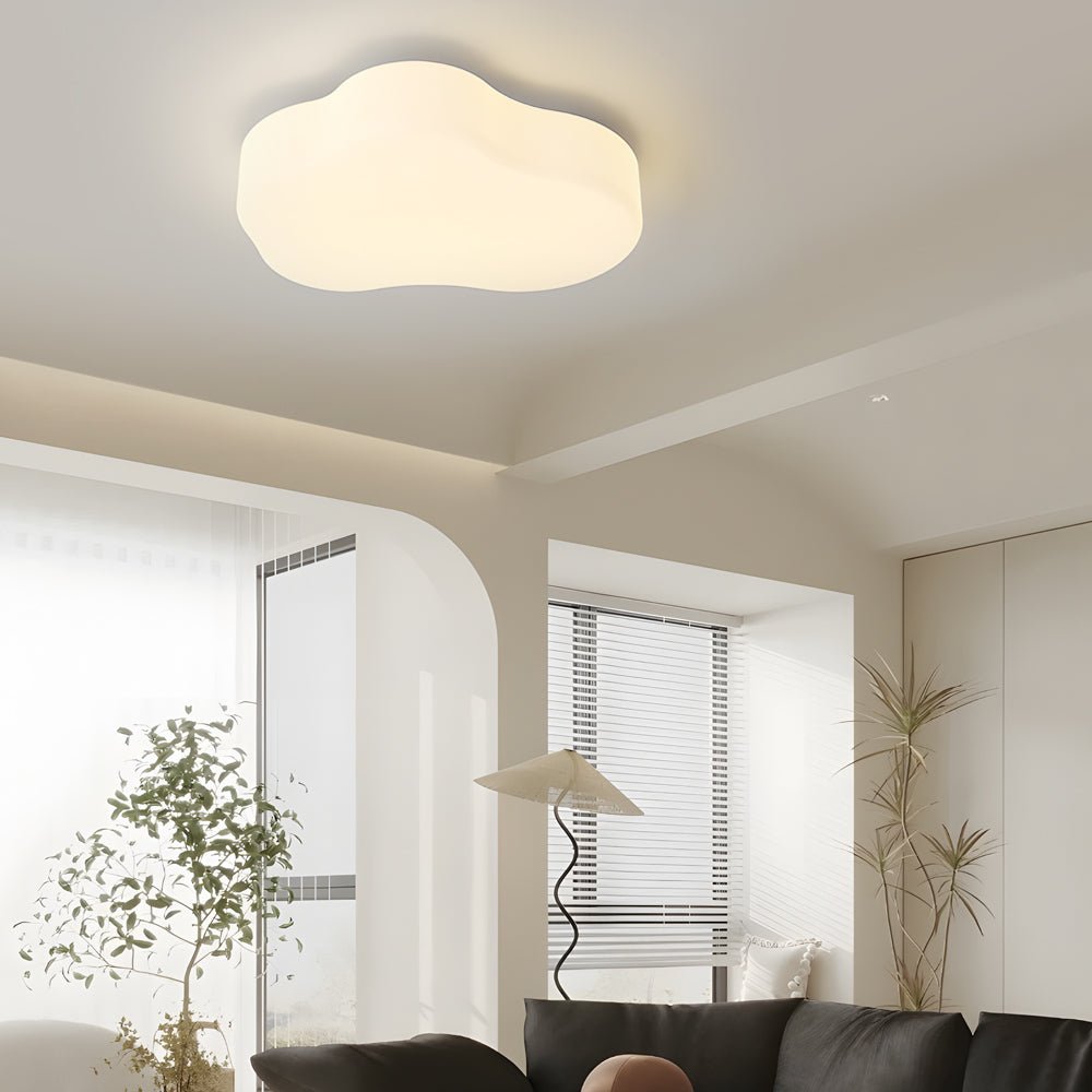 A soft, cloud shaped ceiling light illuminates a modern room, providing a warm and inviting glow in minimalist interiors.