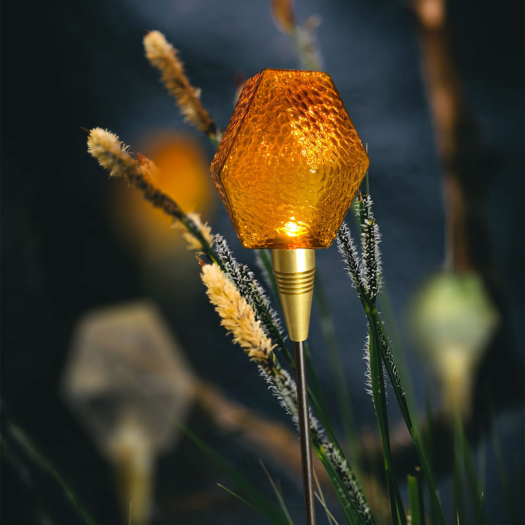 Cluster of amber globe pathway stakes glowing at dusk, forming atmospheric landscape lighting pathway accents.