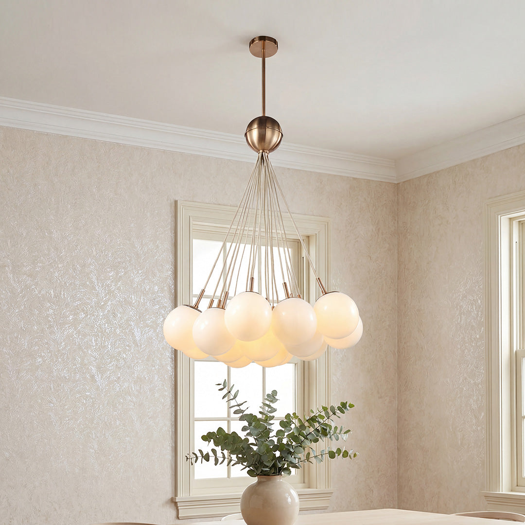 Modern cluster bubble glass chandelier featuring frosted white globes and warm brass hardware suspended in a bright elegant room.