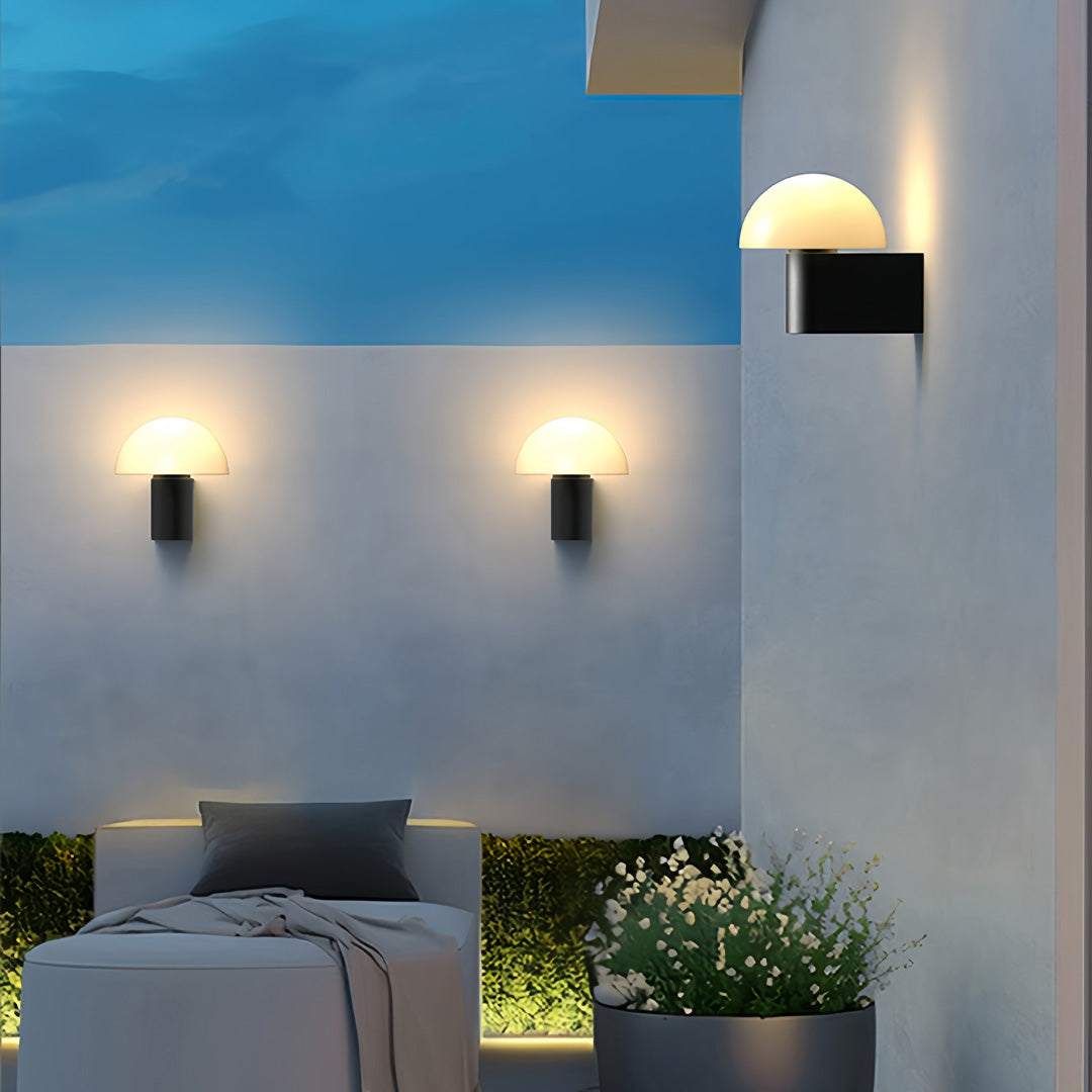 Pair of outdoor wall light sconces mounted on a contemporary exterior wall, lighting up a coastal terrace at dusk.