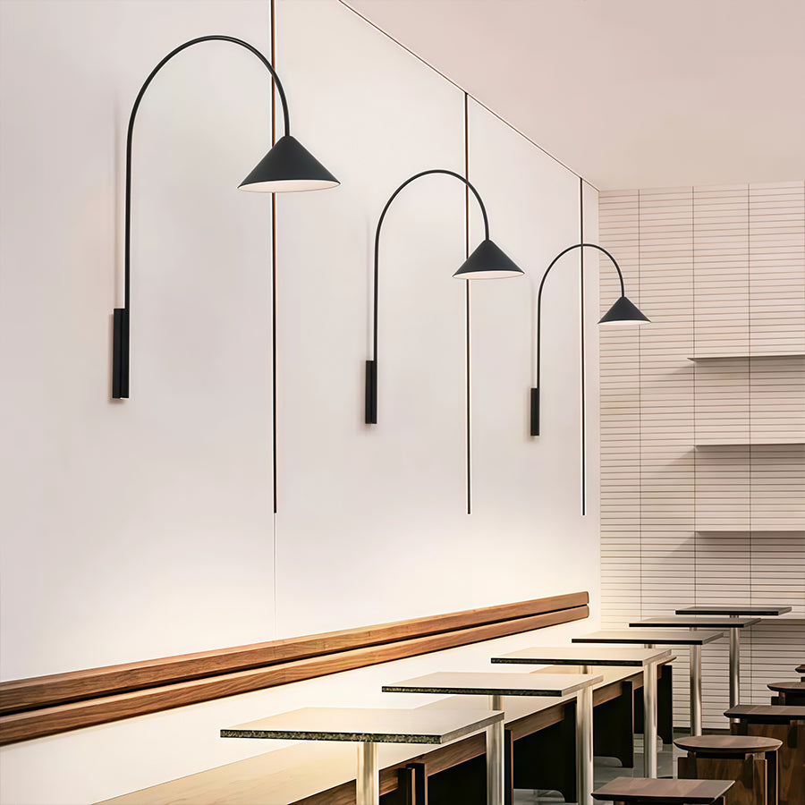 Collection of wall arm lights with varying lengths creating dynamic lighting installation in modern cafe.