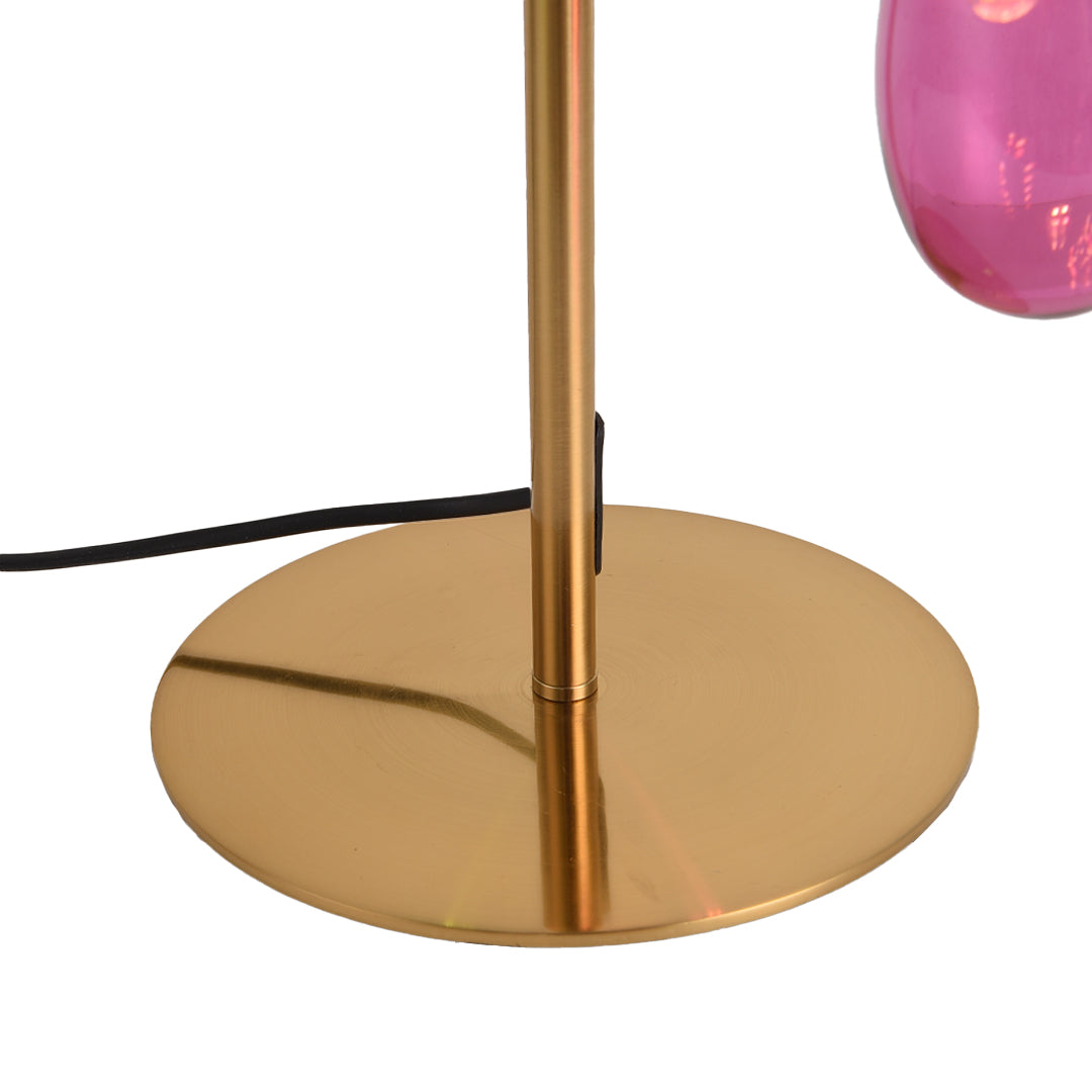 Gold base detail of colored glass table lamp with power cord visible.