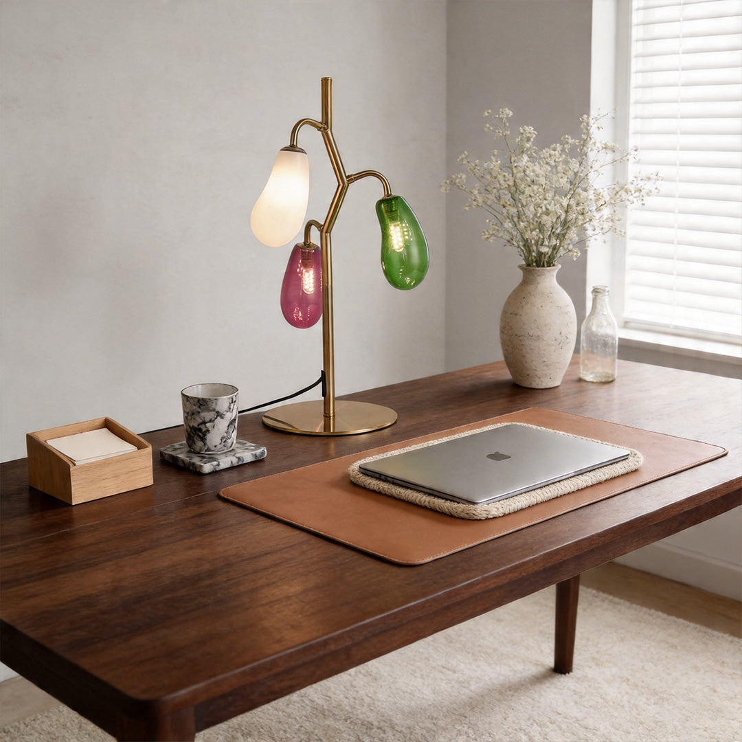 Colored glass table lamp on a desk creating warm ambient lighting.