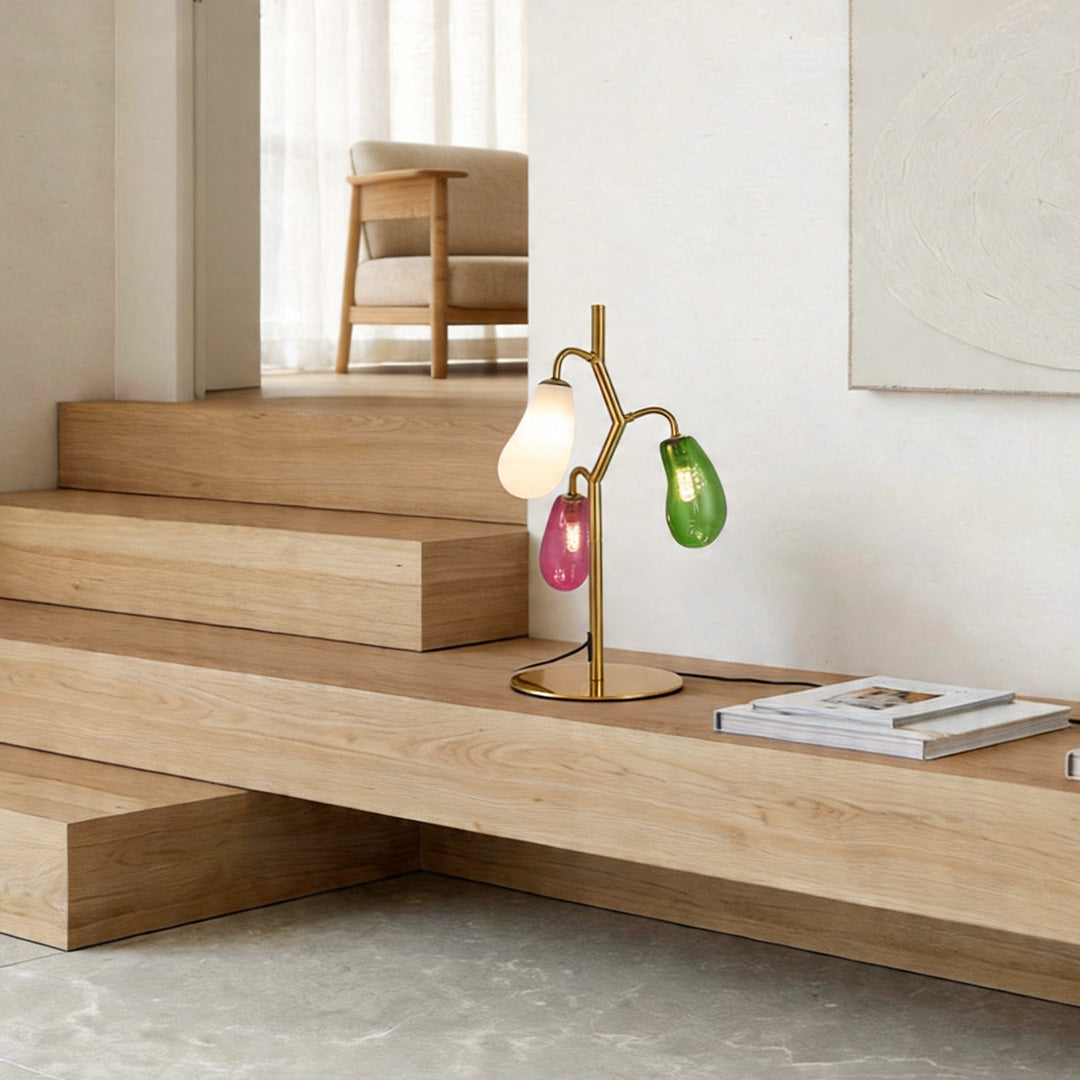 Colored glass table lamp styled on wooden steps in a minimalist interior.