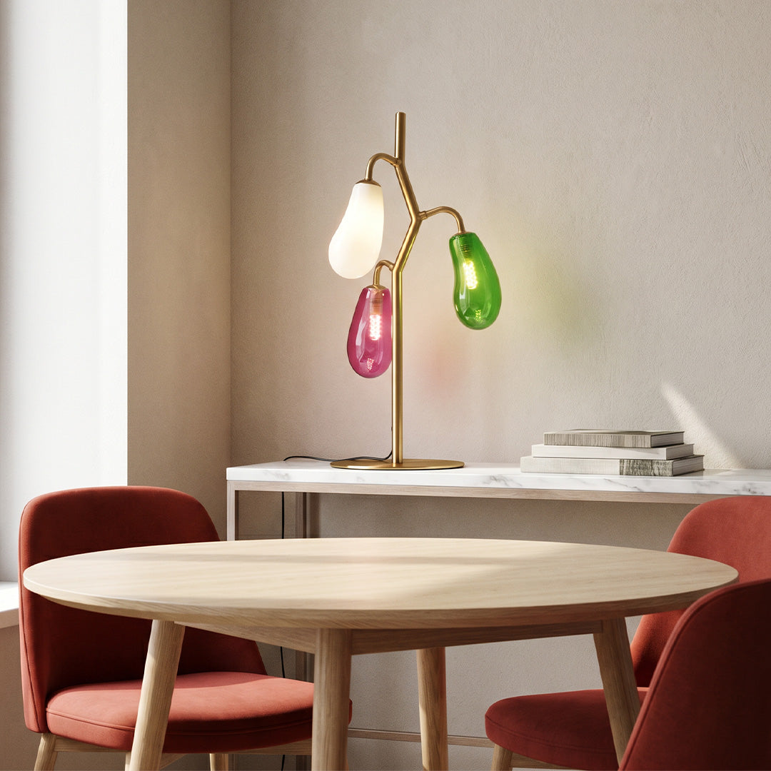 Modern colored glass table lamp on a round table in a cozy seating area.