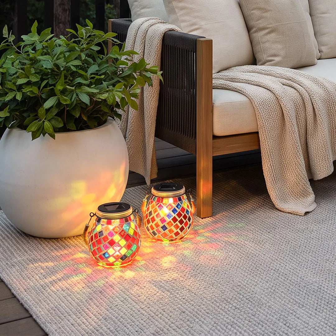 Colored landscape lights with two red mosaic lanterns casting patterned light beside an outdoor lounge chair.