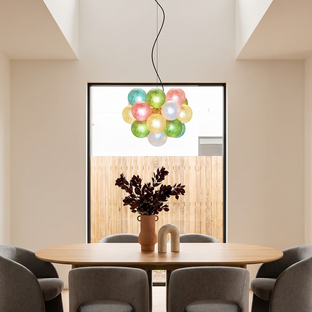 Colorful glass chandelier suspended above a dining table in a contemporary dining room setting.