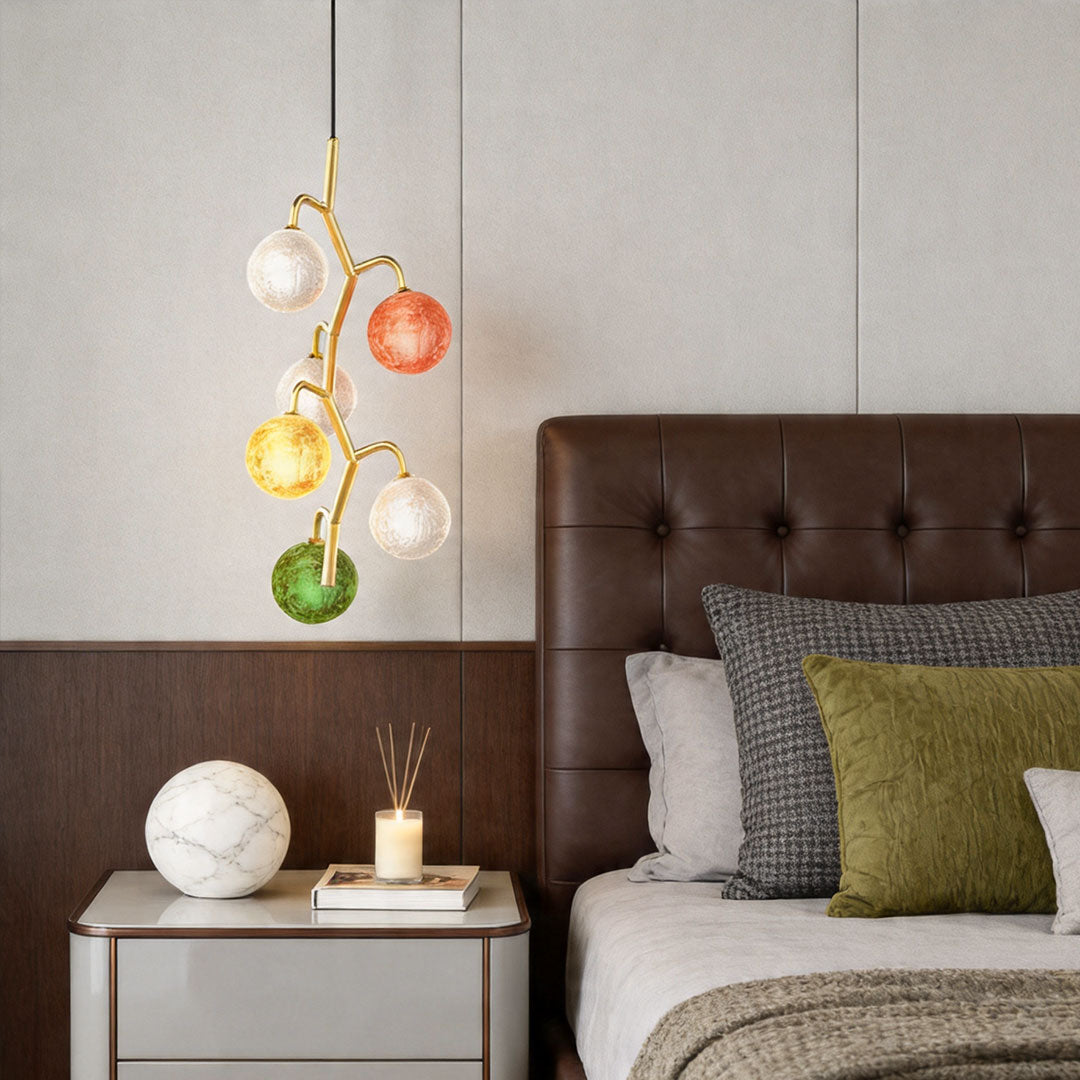 Coloured glass chandelier hanging beside bed adding warm decorative lighting.