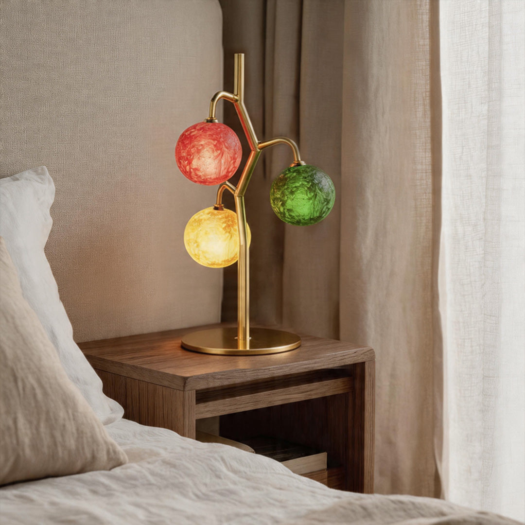Coloured glass globe table lamp beside bed creating warm ambient glow.