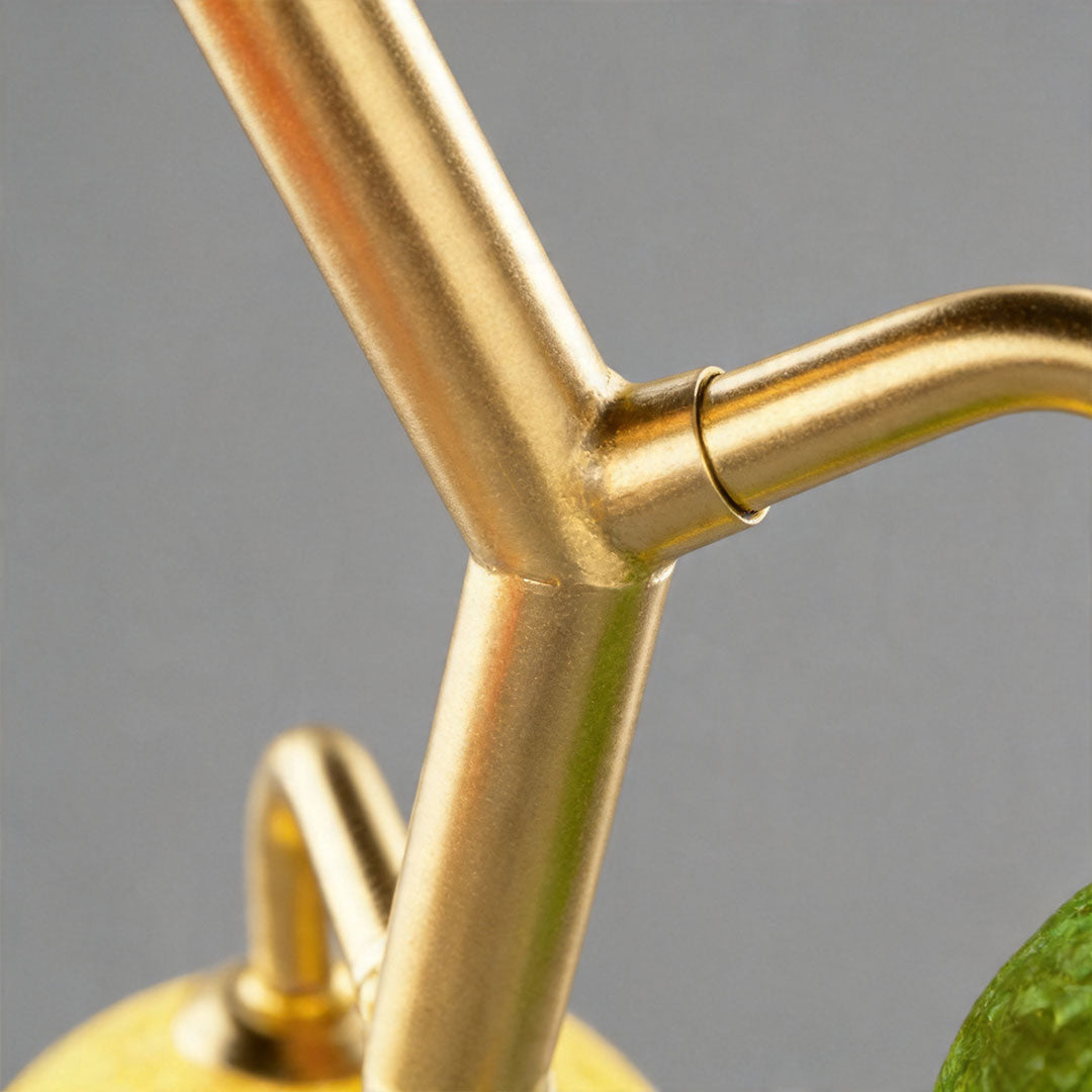 Close-up of brass structure of coloured glass table lamp with curved arm design.