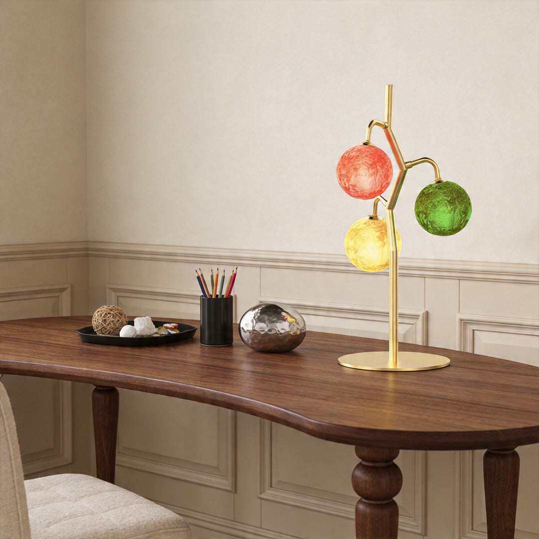 Modern coloured glass table lamp placed on wooden desk with decorative lighting effect.