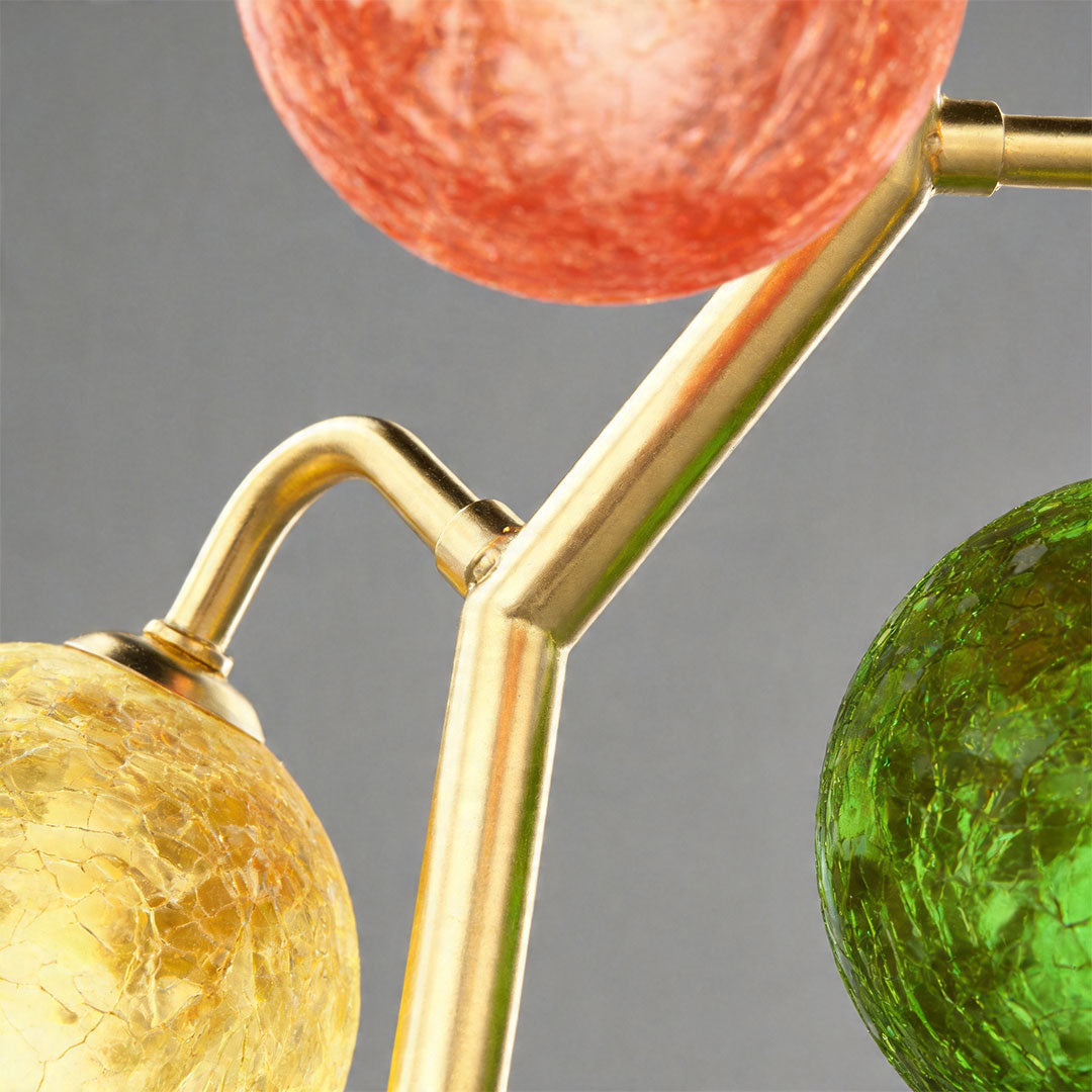 Close-up of coloured glass globes on brass table lamp showing vibrant textures.