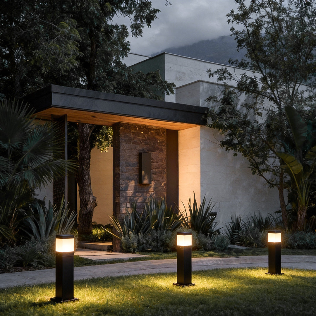 Commercial bollard lights with sleek black finish illuminating a modern house pathway and garden area.