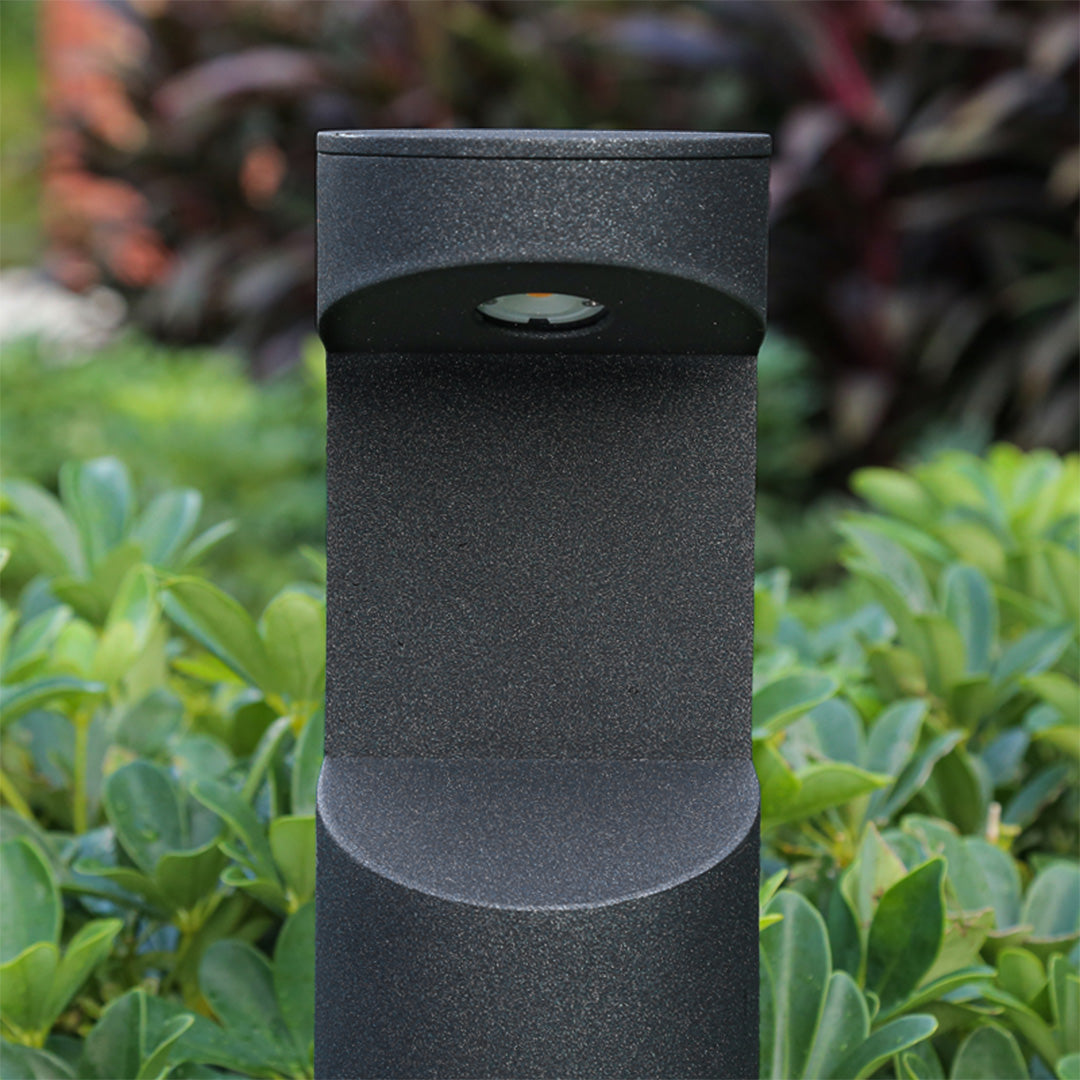 Contemporary black bollard lights integrated into landscaped commercial pathway design