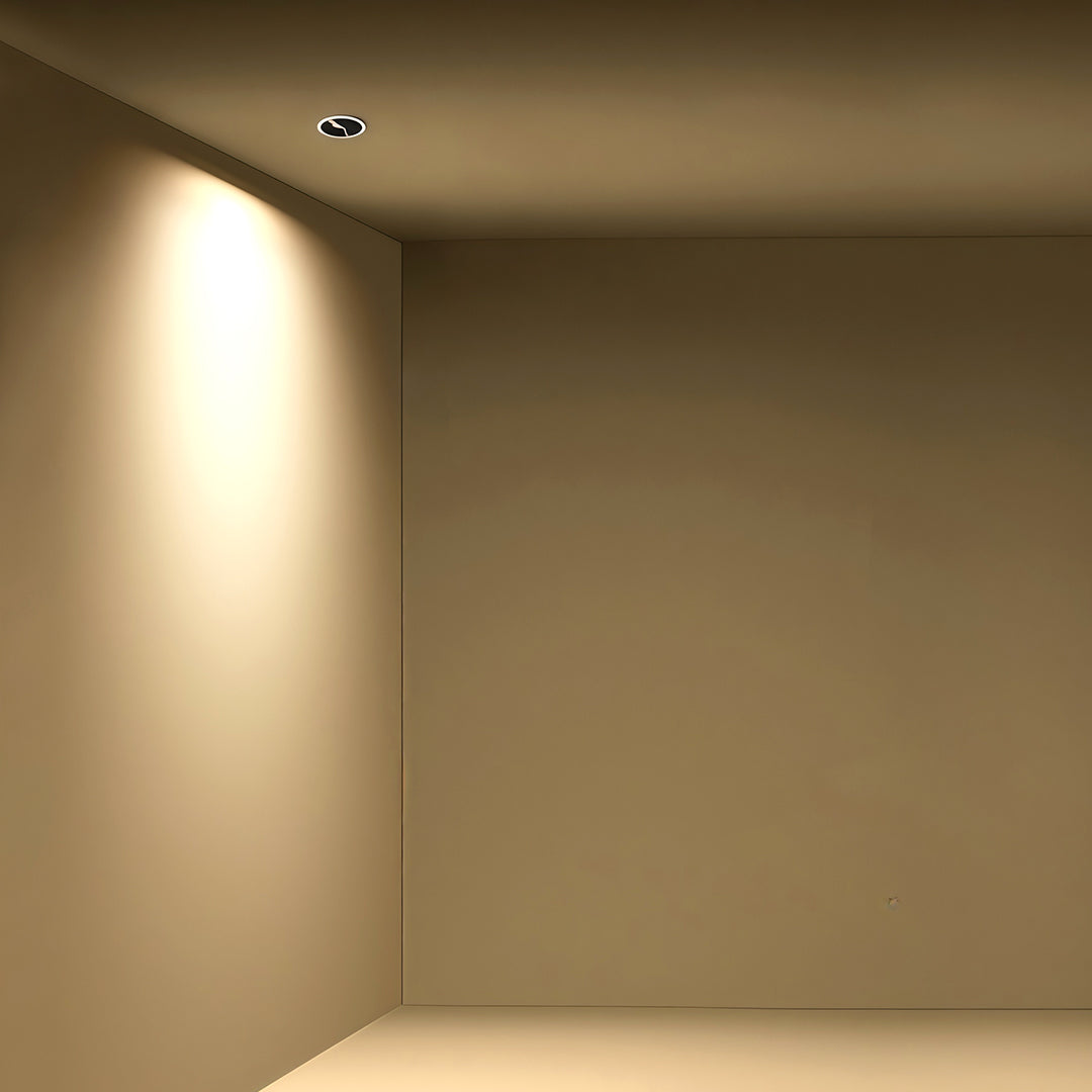 Compact adjustable spotlights creating warm ambient glow along corridor wall with glass shade chandelier influenced design.