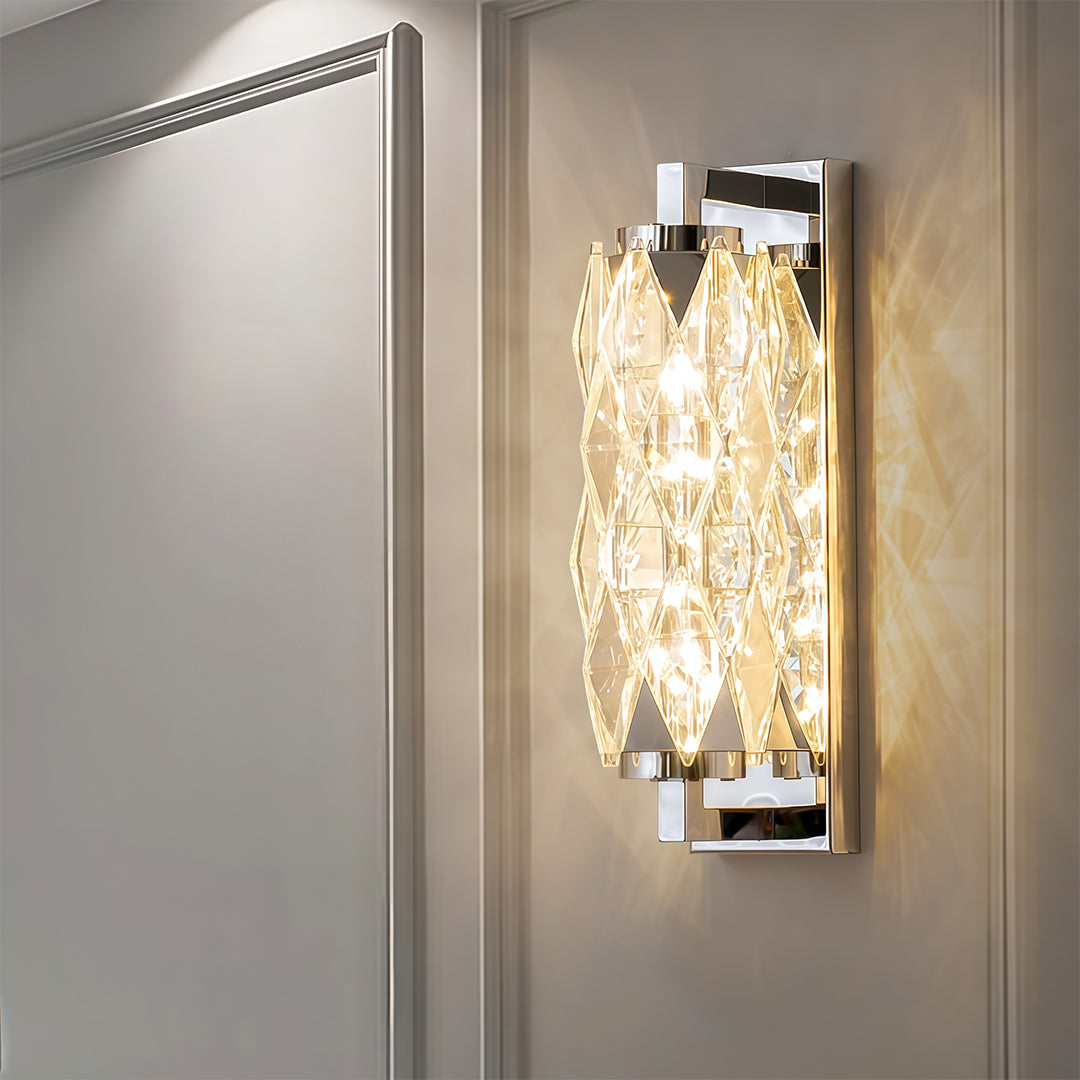 Compact modern wall light with polished chrome and crystal glass creating sparkle on white surface.