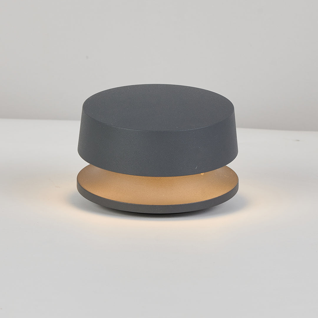 Compact round LED path light fixture with sleek black finish and integrated warm lighting element