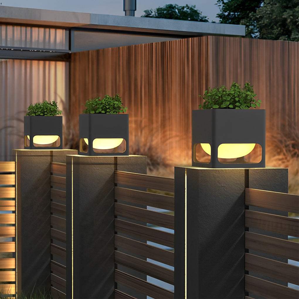 Concrete pillar lights adding ambiance to a wooden fence and garden area.