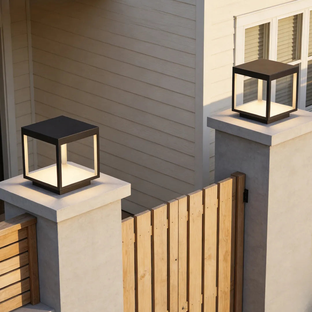Concrete pillar lights mounted on square fence posts beside a modern home entrance.