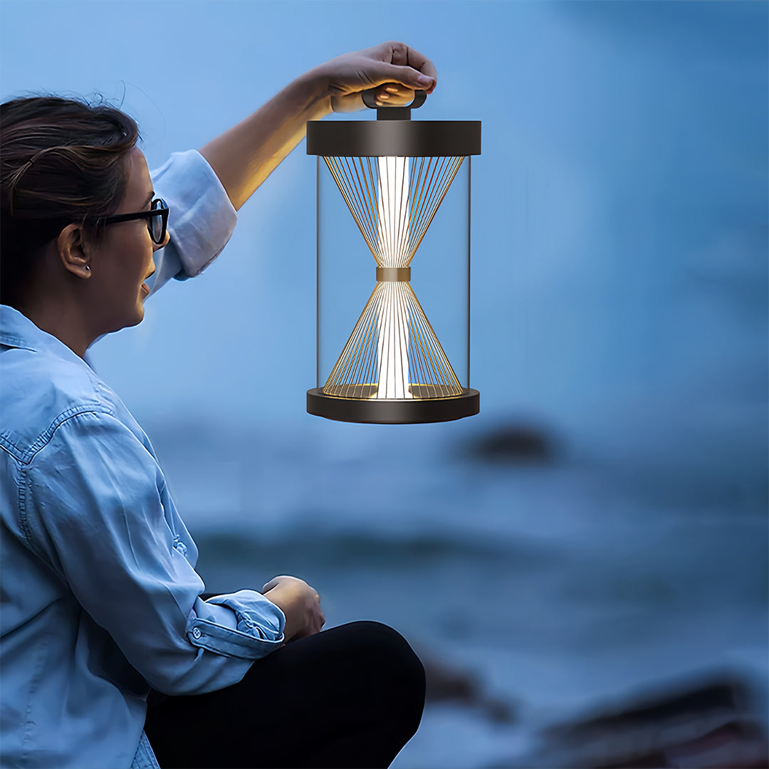 Black outdoor lantern positioned at the bottom of concrete stairs on a modern patio, providing pathway safety and accent light.