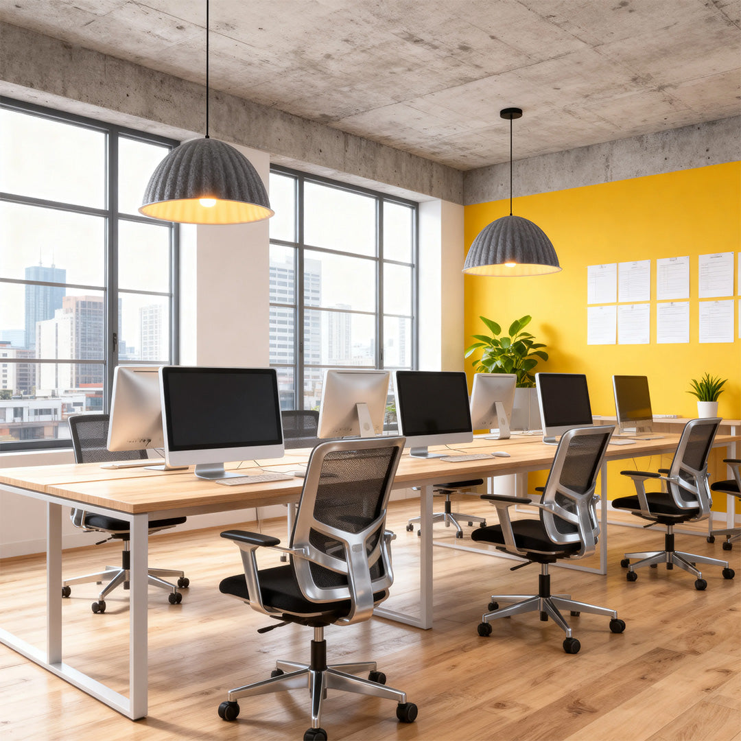 Concrete and yellow accented office features two prominent gray pendant light shades over a row of computer workstations.