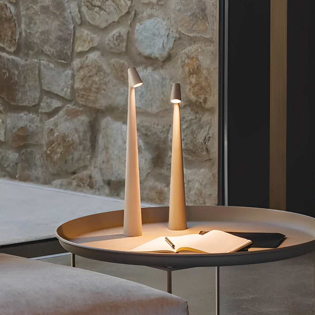 Minimalist cone shaped table lamps displayed on a round coffee table in a stone interior.