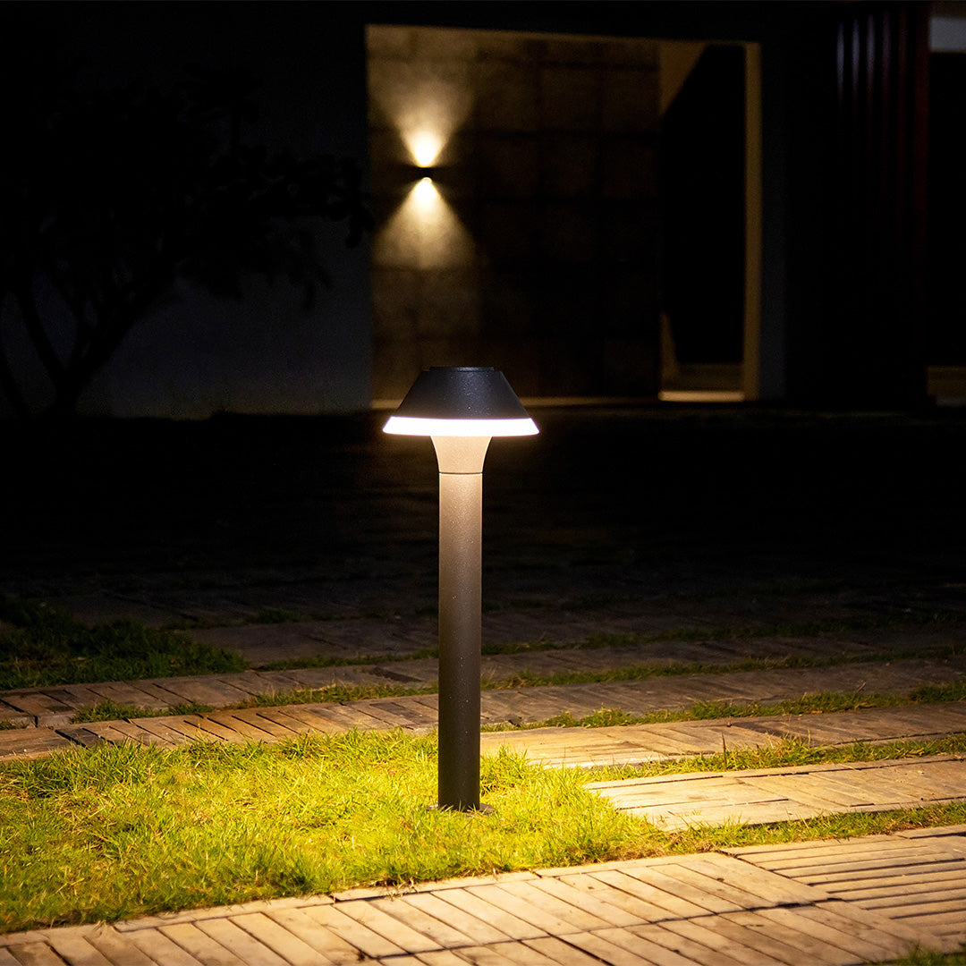Modern cone-topped bollard light providing ambient lighting in residential garden