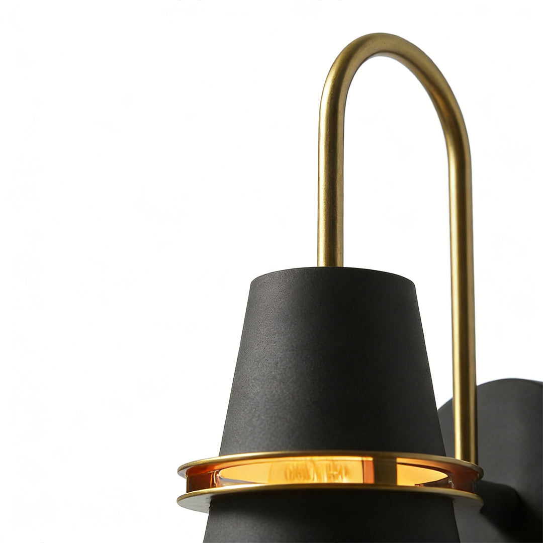 Black cone wall lamp with elongated brass loop mounted on neutral interior wall.
