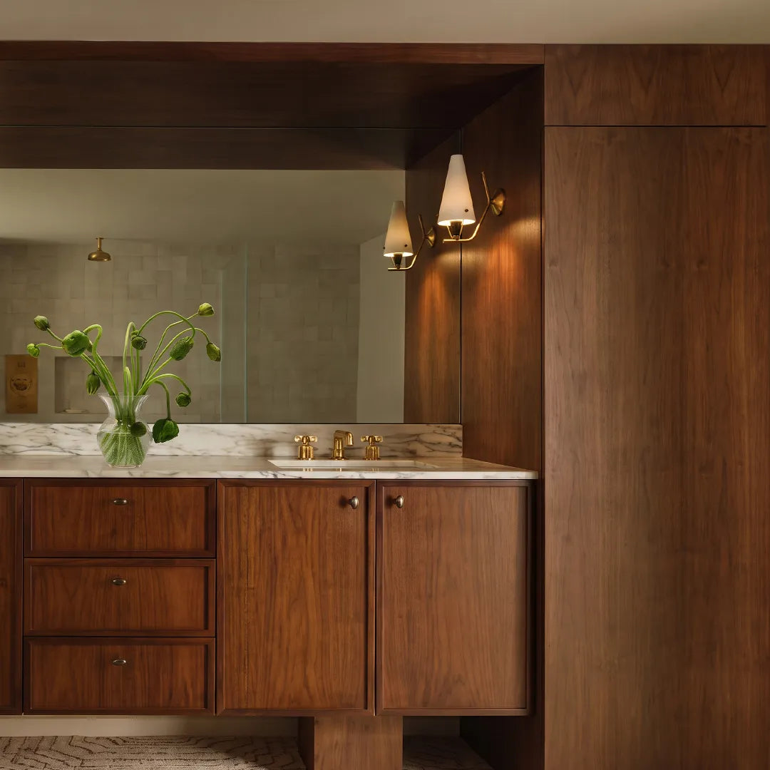 Cone wall light installed above a bathroom vanity with a white shade and brass details.