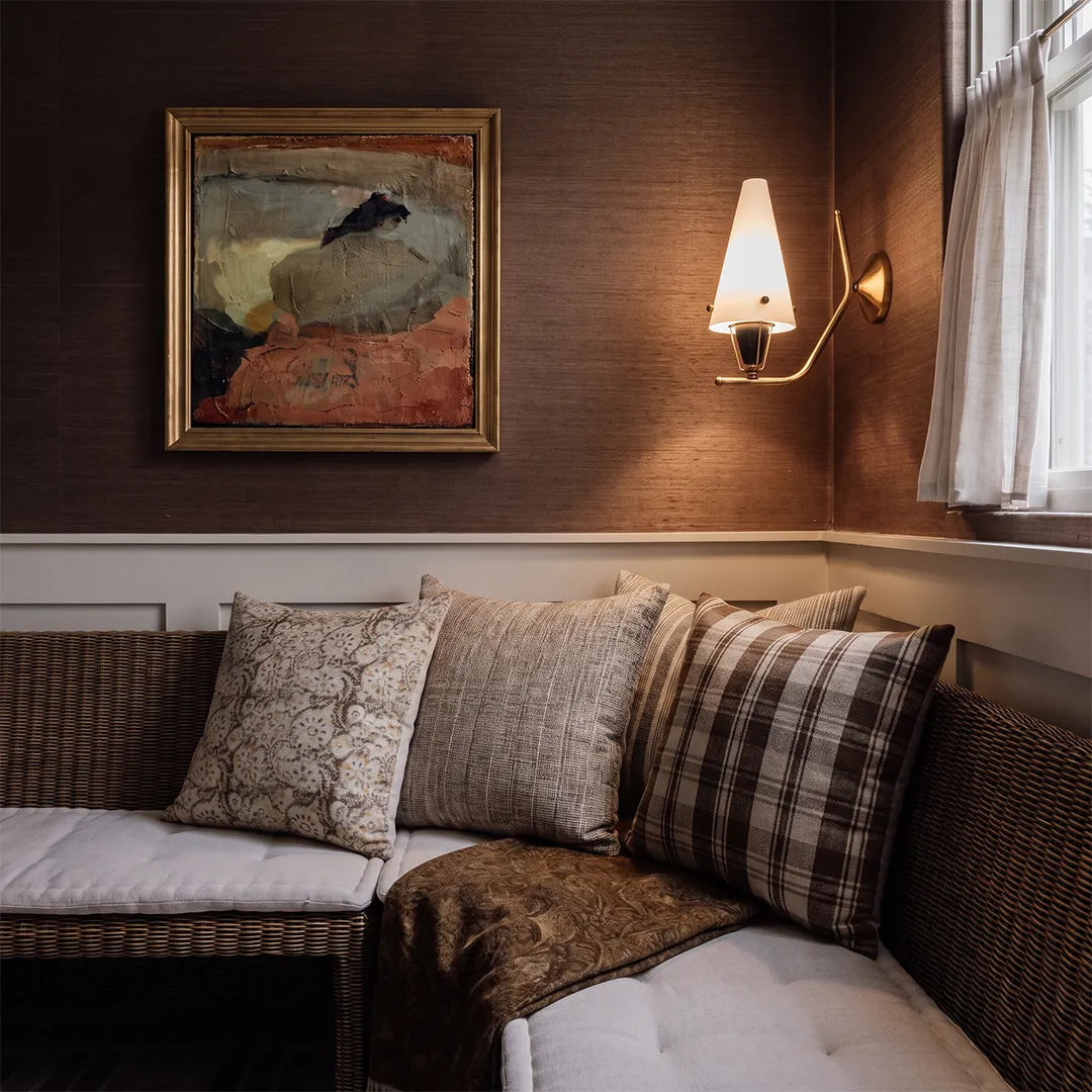 Cone wall light installed on a dark bedroom wall beside artwork and a cozy seating area.