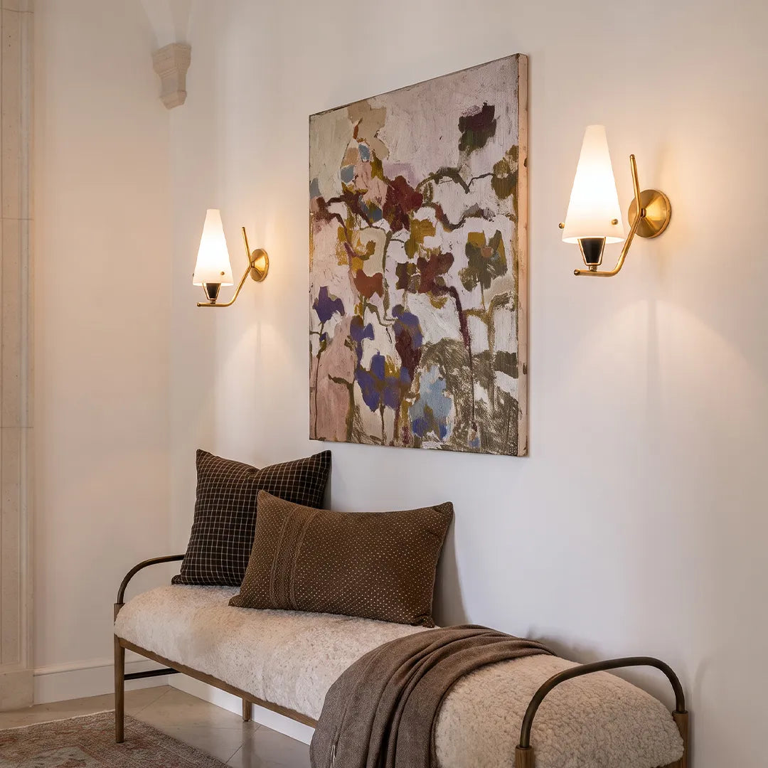 Cone wall lights installed on a living room wall beside artwork with a modern brass finish.