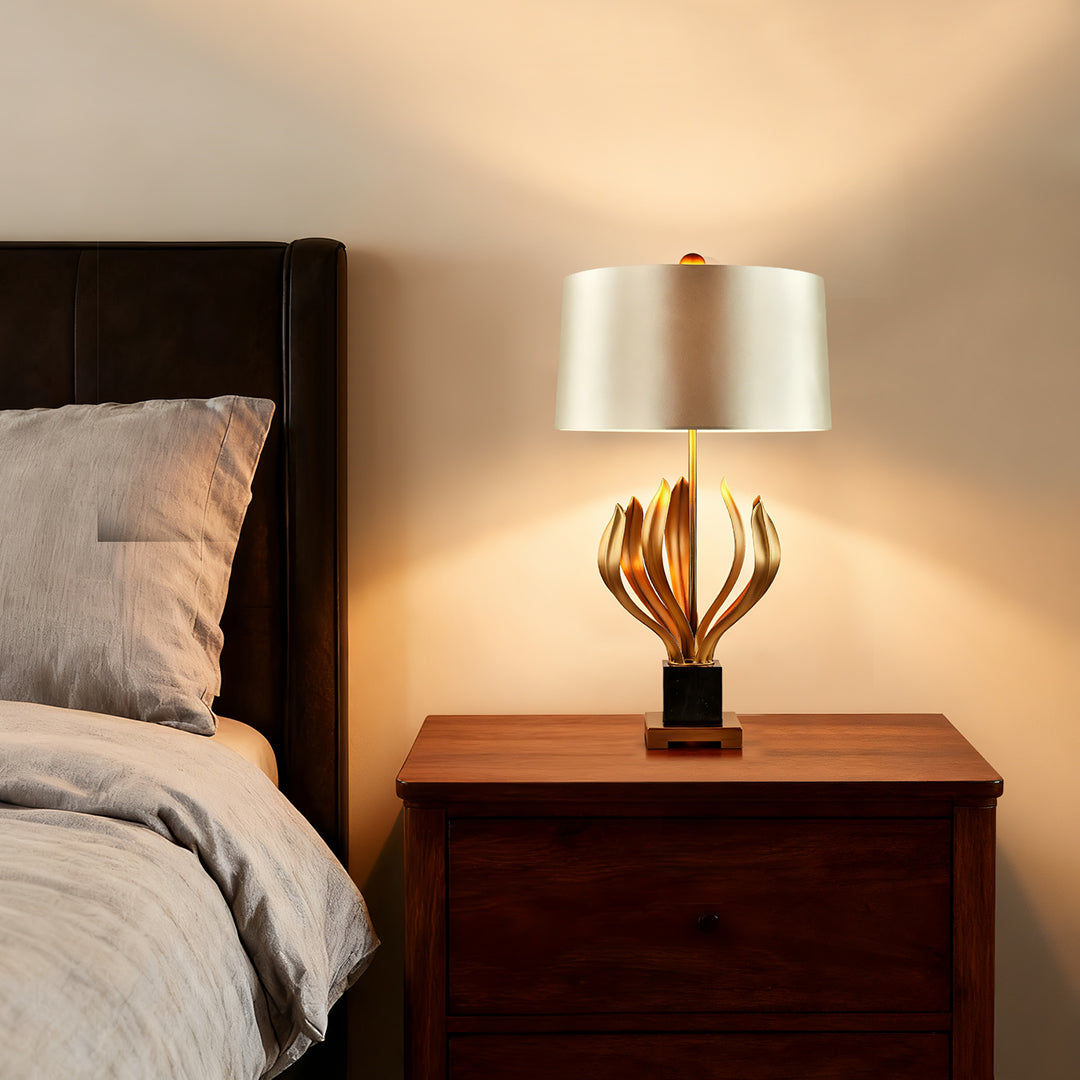Vintage gold metal table lamp with sculptural base and beige lampshade in a cozy bedroom
