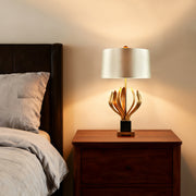 Vintage gold metal table lamp with sculptural base and beige lampshade in a cozy bedroom