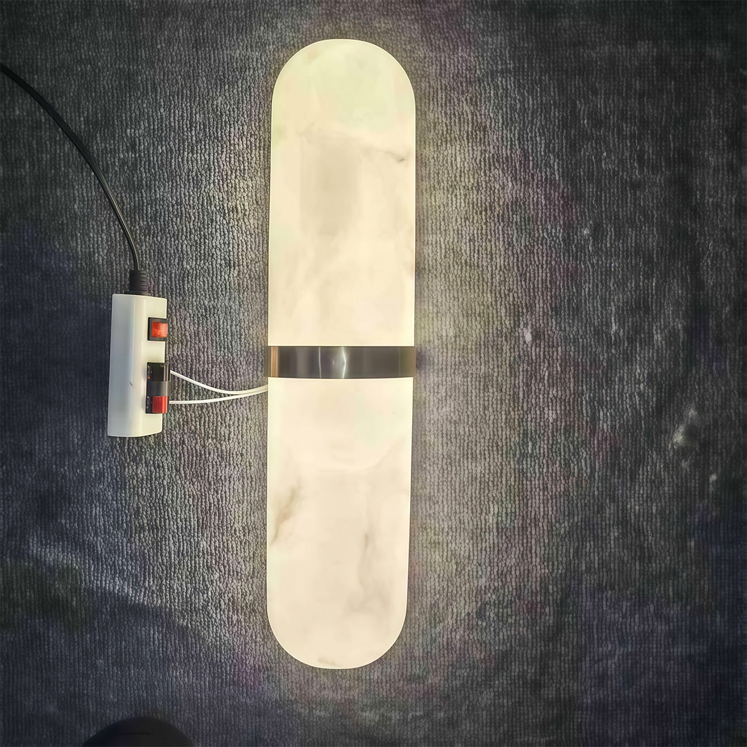 Contemporary art wall lighting with glass shade chandelier aesthetic creating dramatic lighting effect on textured dark wall surface.