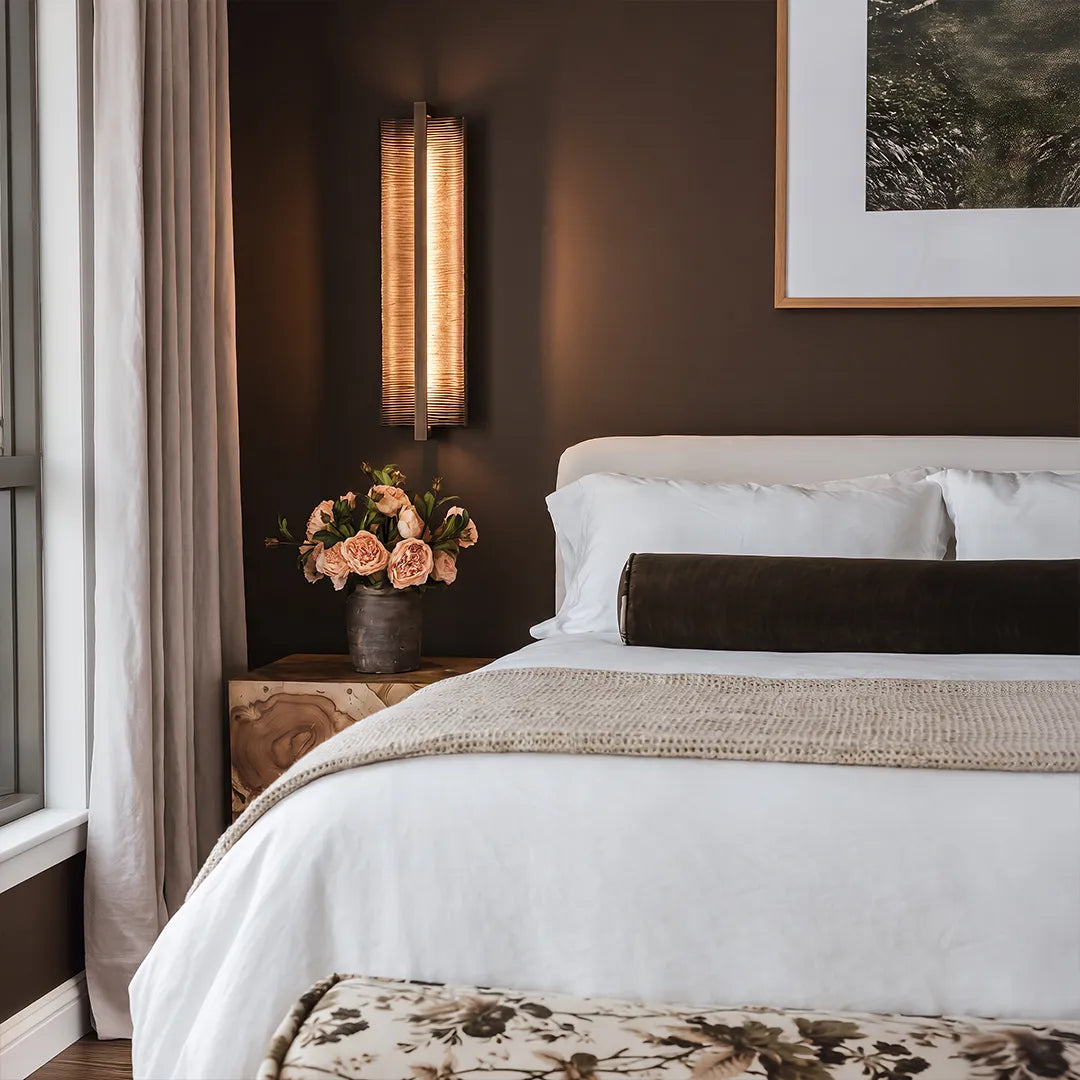 Contemporary bedroom with vertical wall sconce upholstered bed and warm lighting