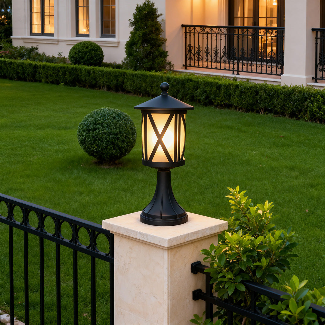 Contemporary black outdoor pillar light brightening lawn area on decorative pier near iron fencing