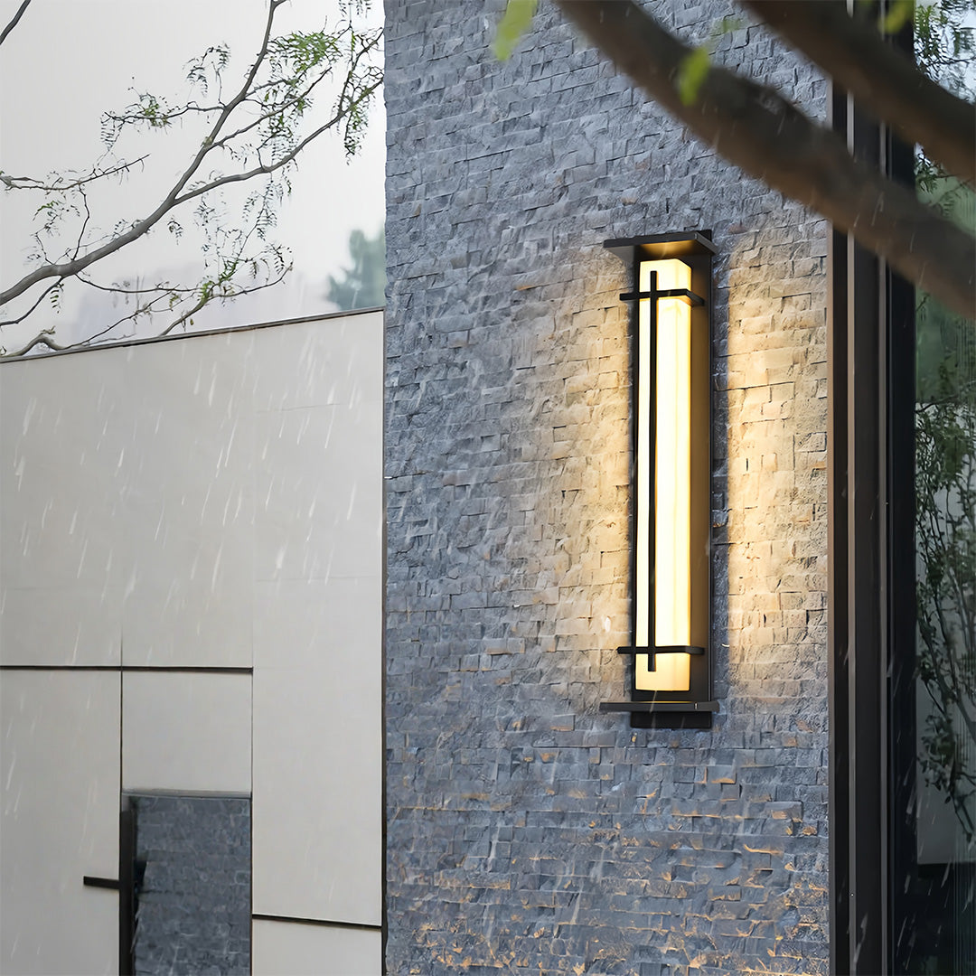 Contemporary black outside wall lights illuminating a textured stone wall exterior.