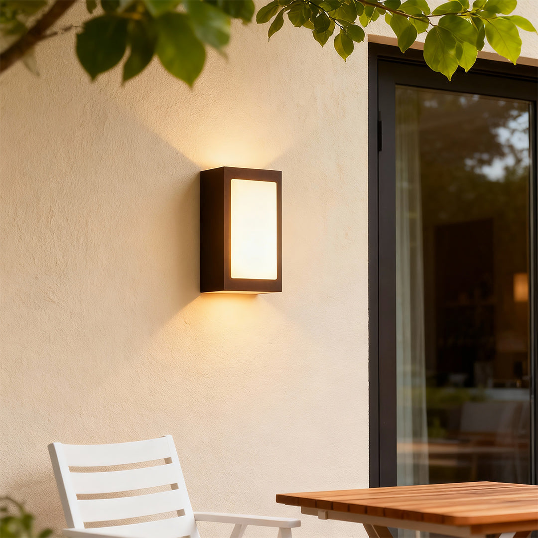 Contemporary black sconce wall lights featuring glass shade chandelier styling creating warm ambient glow on outdoor patio wall.