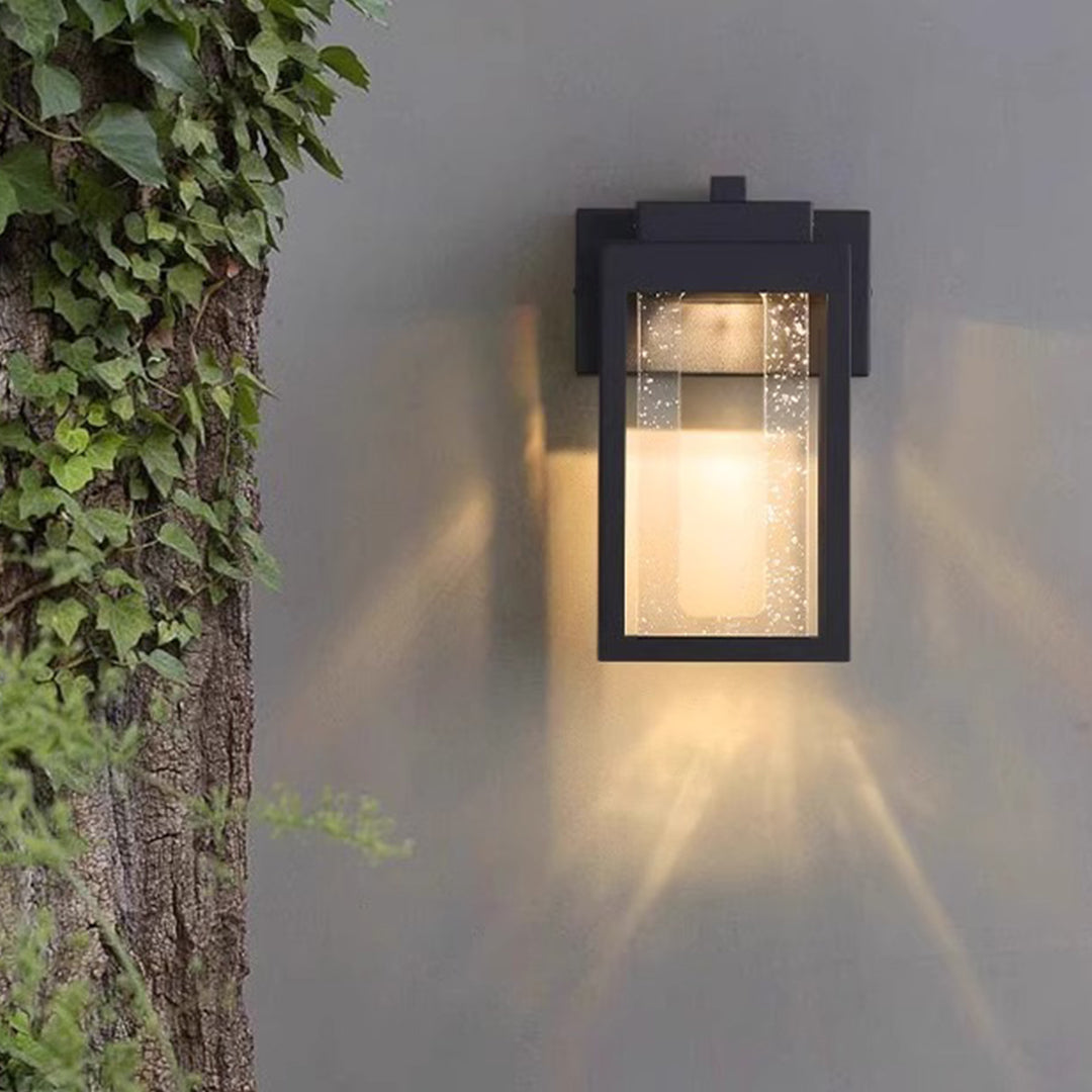 Contemporary black outdoor wall sconce with frosted glass creating soft downward lighting