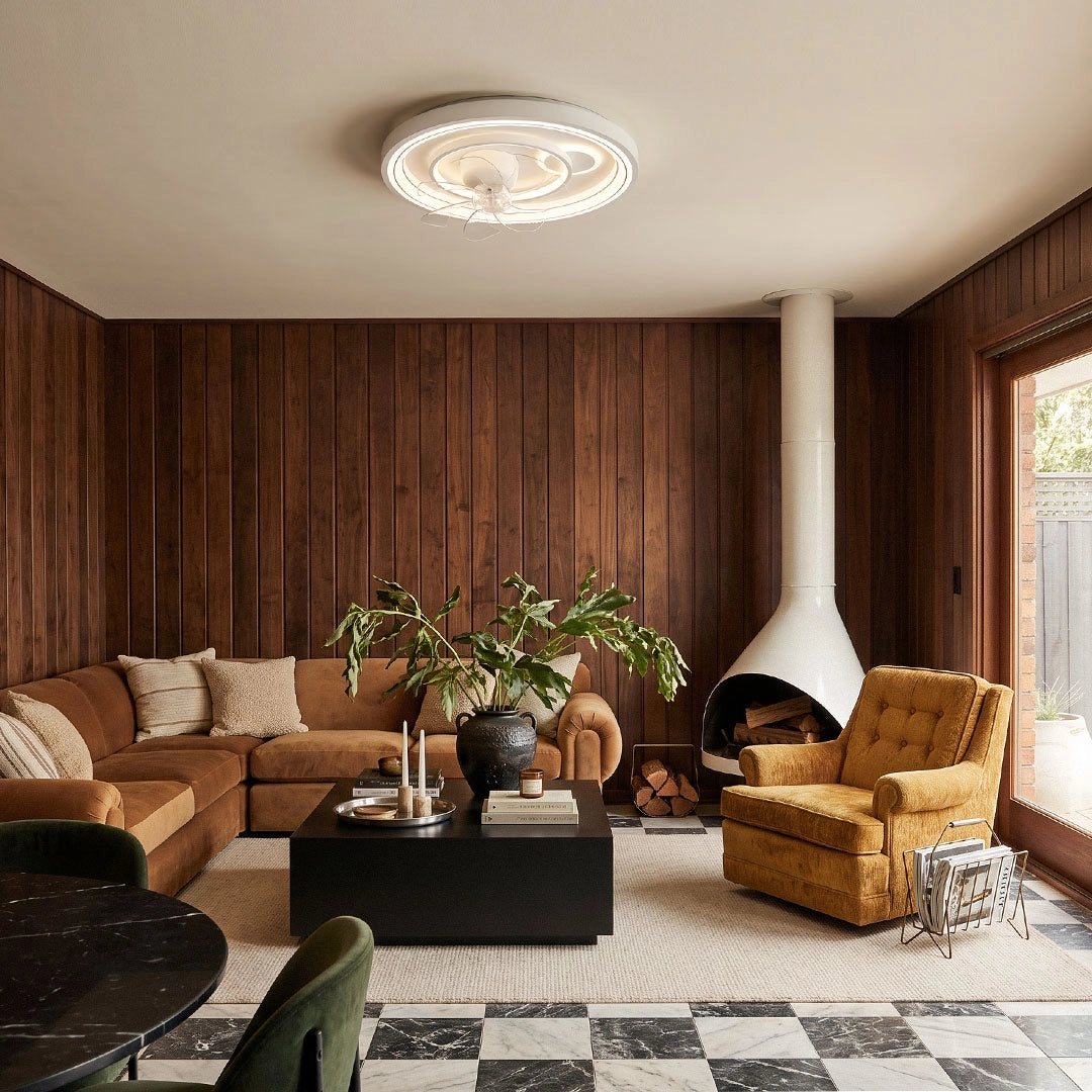 Contemporary ceiling fans with light mounted in a warm living room with wood paneling, a fireplace, and cozy lounge seating.