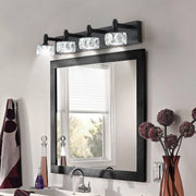 Contemporary crystal bathroom vanity light featuring glass shade chandelier aesthetic above black-framed mirror with decorative accents.