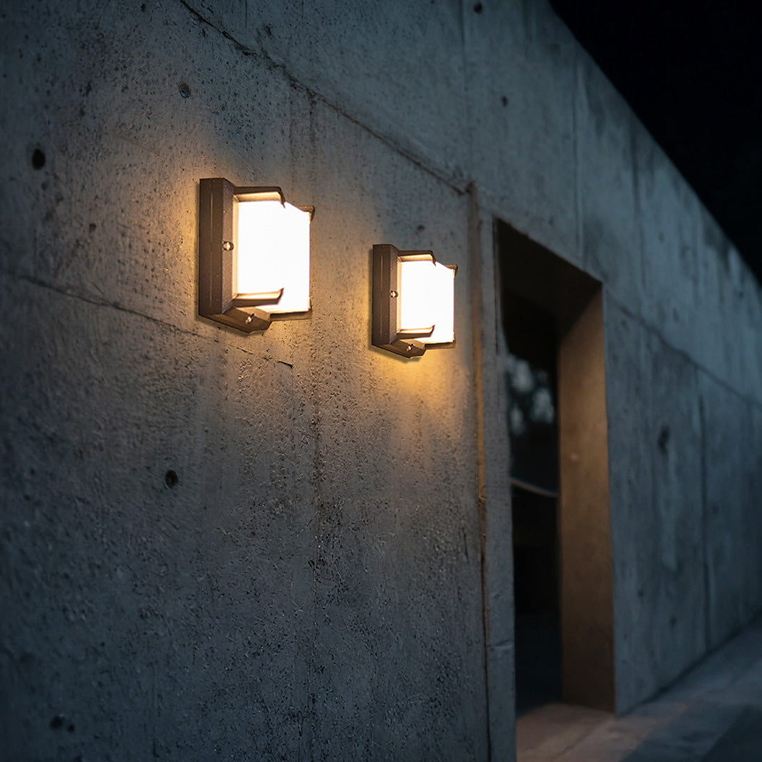 Two contemporary cube Black Outdoor Wall Light units mounted on a textured gray concrete wall at night.