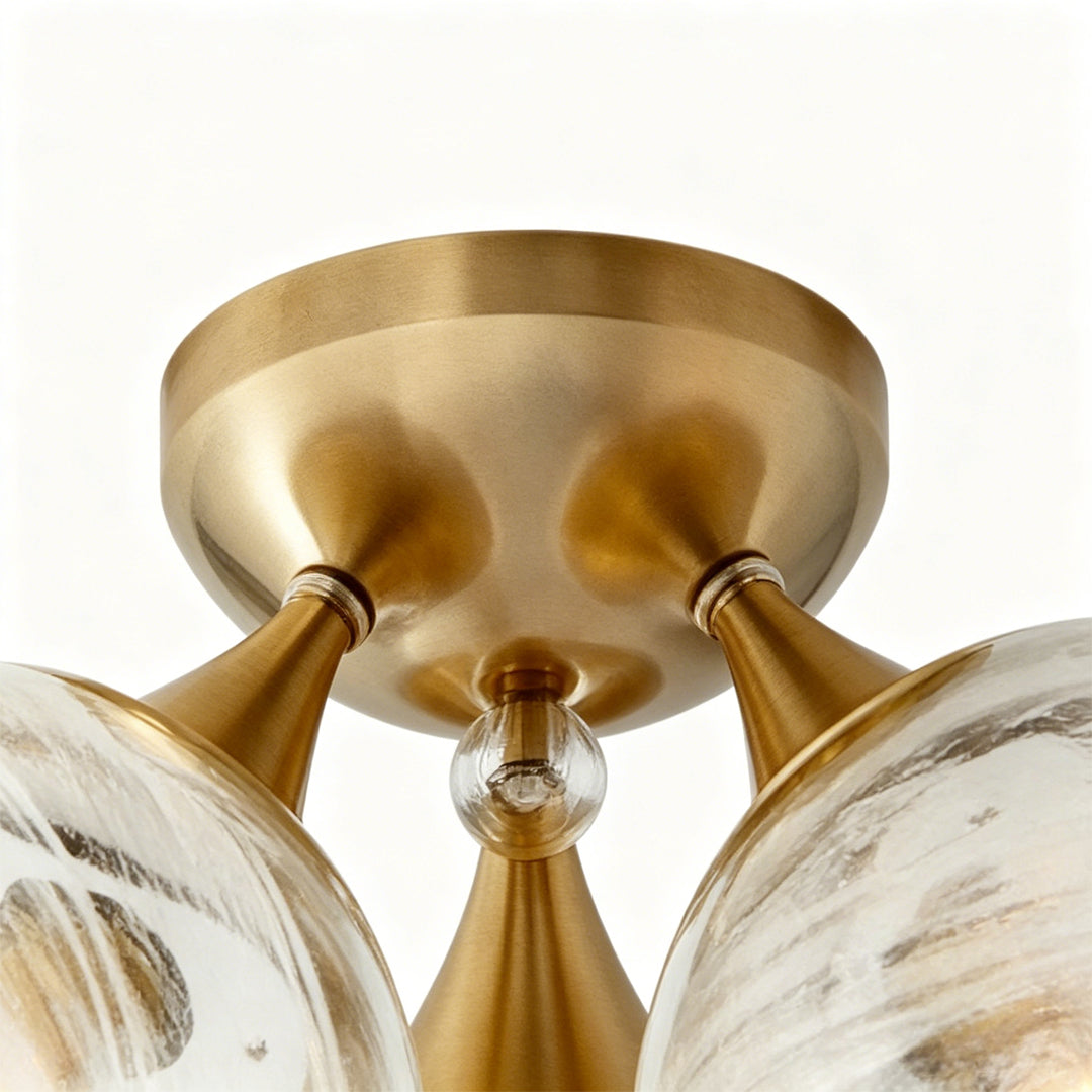 Contemporary flush mount light fixtures close-up showing brushed brass canopy and glass globe details.
